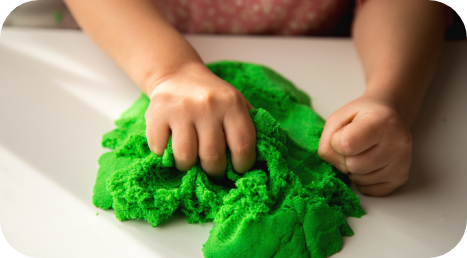 Close-up of a child’s hands playing with green sensory putty during occupational therapy