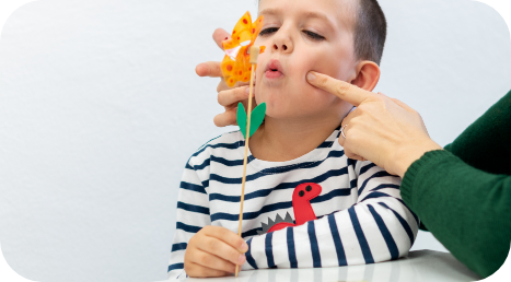 Speech-language pathologist helping a child practice mouth and breathing exercises