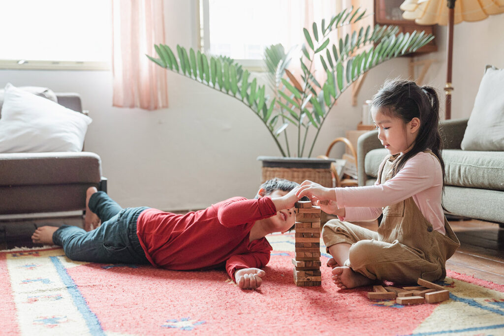 two children playing with Jenga blocks on the ground